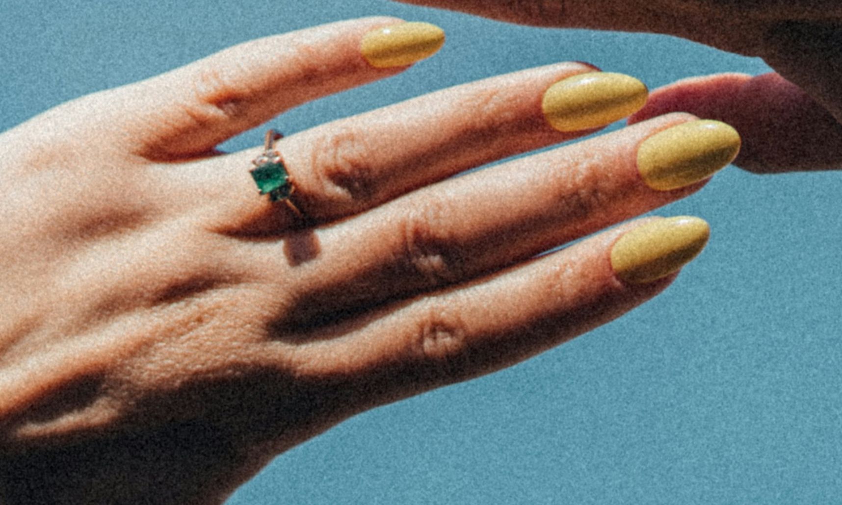 hand with butter yellow nails held up to the sky