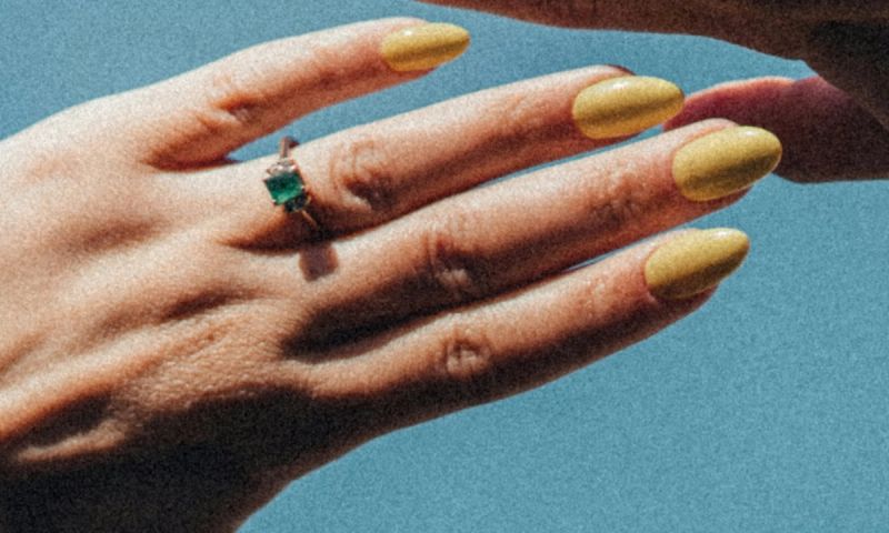 hand with butter yellow nails held up to the sky