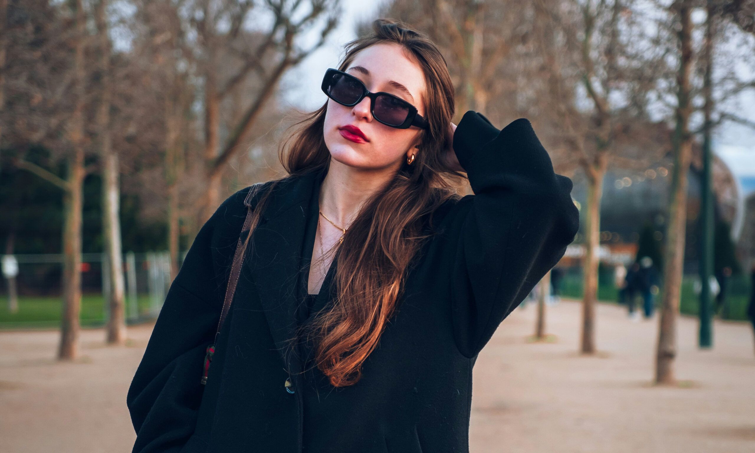 Parisian woman walking outdoors wearing red lipstick and black coat