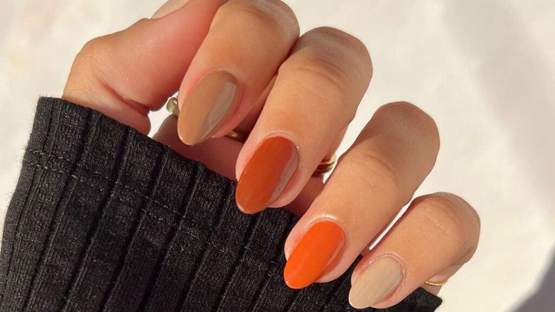 close-up of hands wearing brown and orange nail polishes