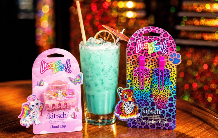 Kitsch x Lisa Frank hair clips flanking a teal cocktail with an orange slice and umbrella garnish at Broken Shaker