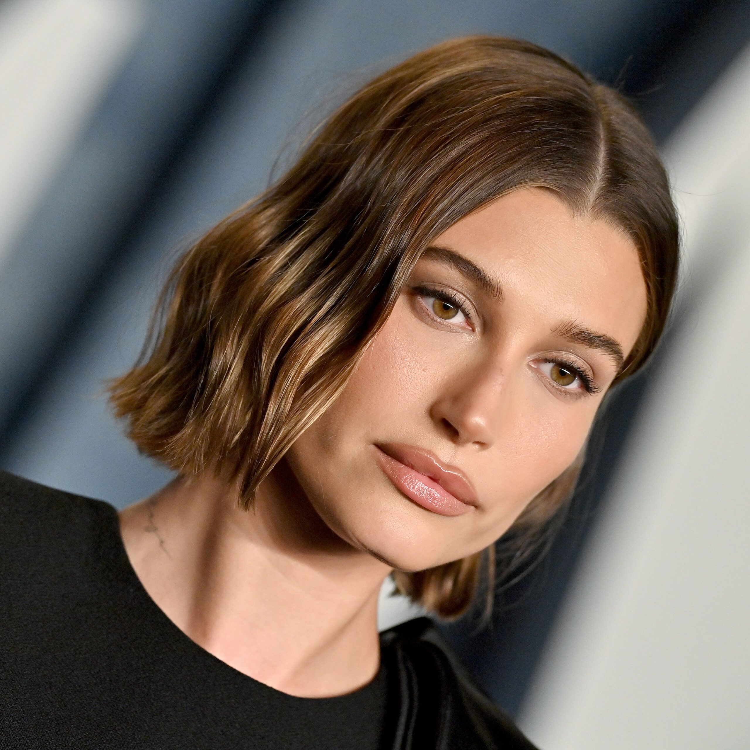 Hailey Bieber with short wavy hair wearing a black dress