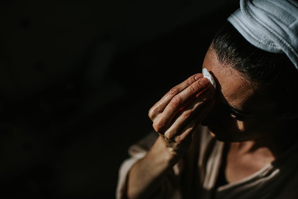 Simple image of a woman rubbing her forehead with a cotton ball. Space for copy.
