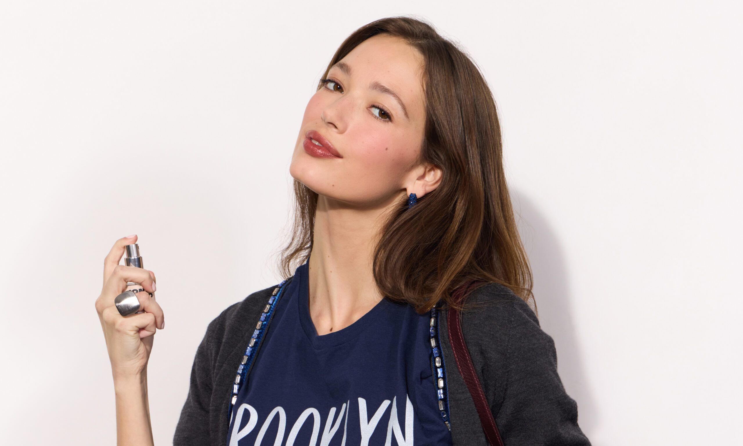 brown haired woman spraying Jones Road BKLYN fragrance