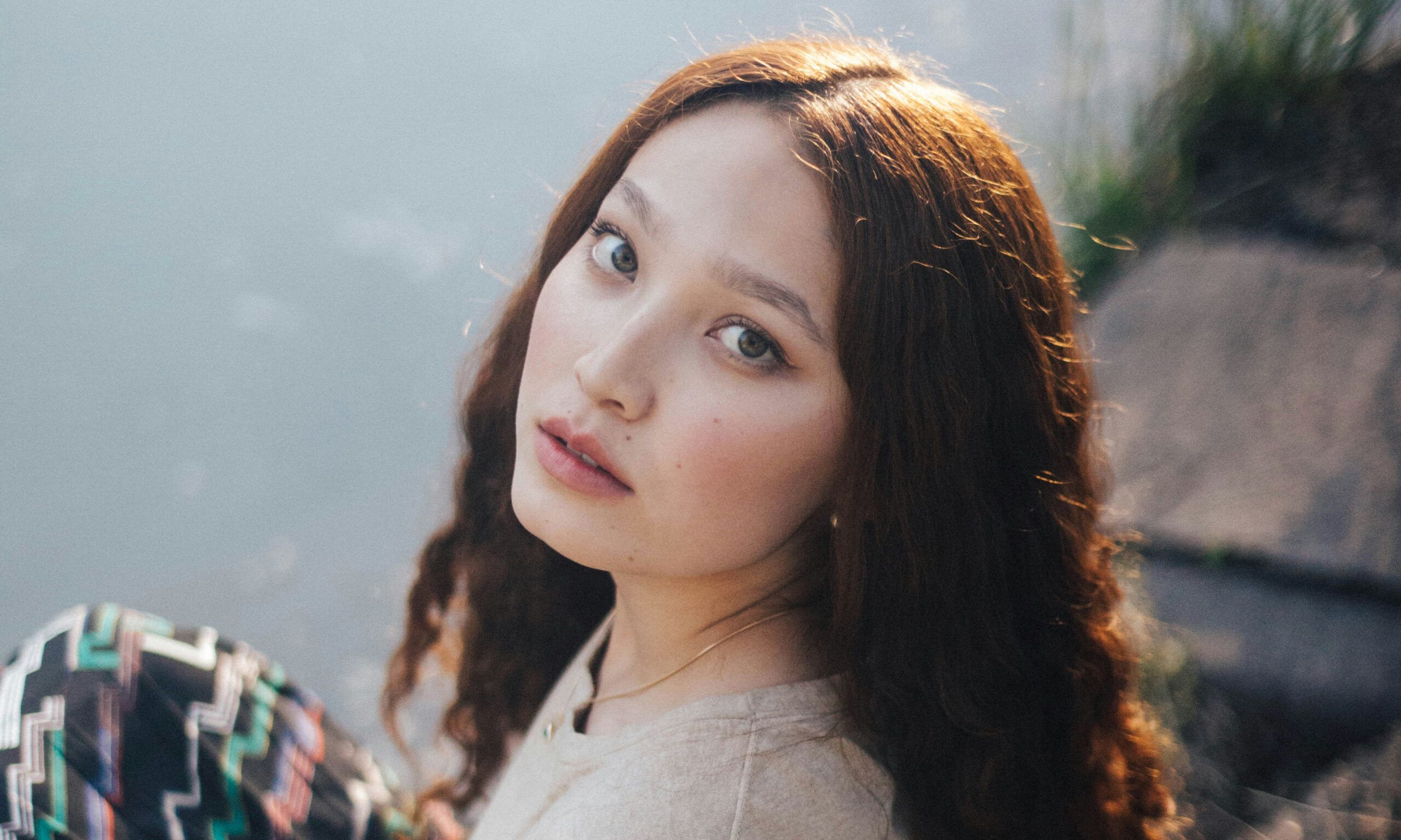 woman in grey shirt sits on river bank
