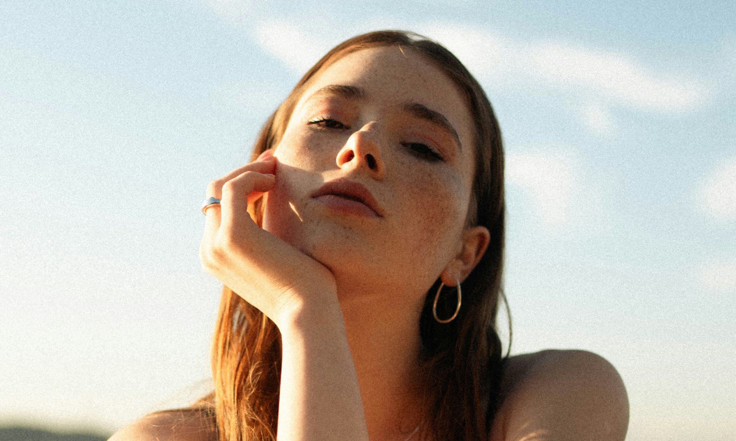 young woman's hand on face sitting in the sun