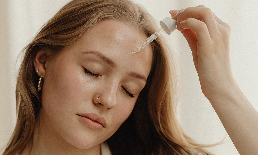 woman putting serum on her forehead