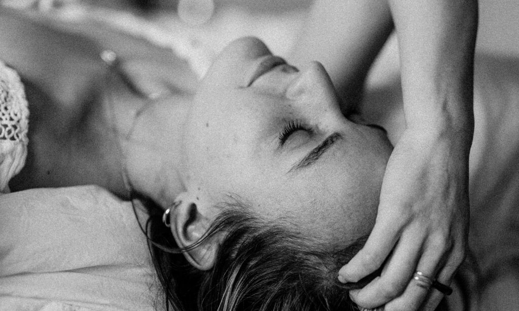 black and white image of woman laying down with hand on her head