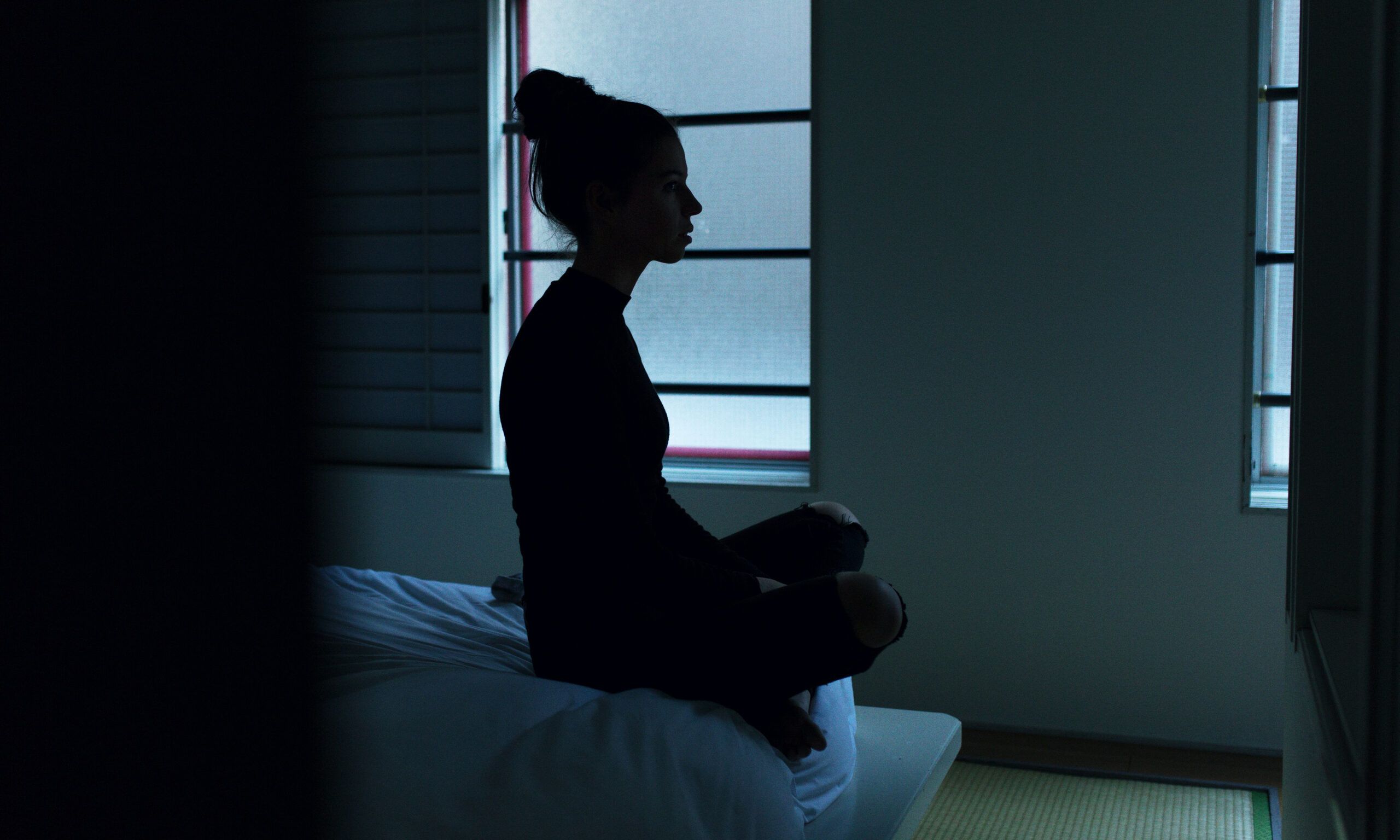 woman sitting on bed in dark