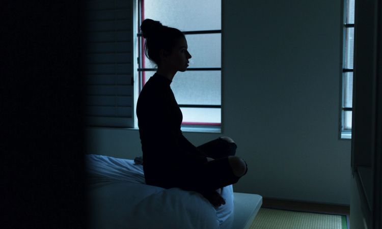 woman sitting on bed in dark