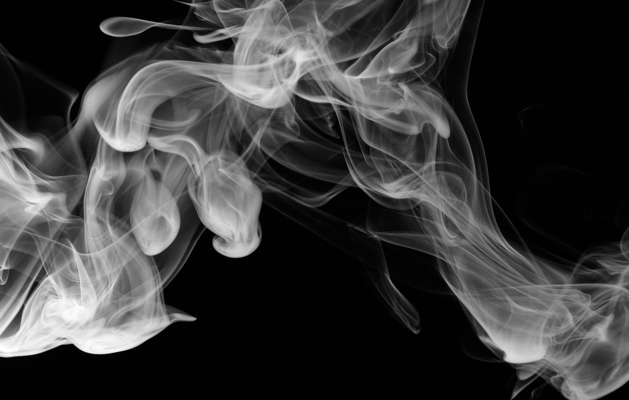 Wisps of white smoke curling and swirling against a black background.