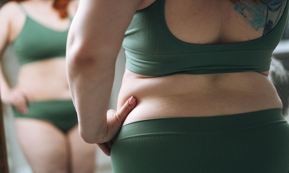 Self loving plus size young woman in underwear looking at mirror in bedroom at home