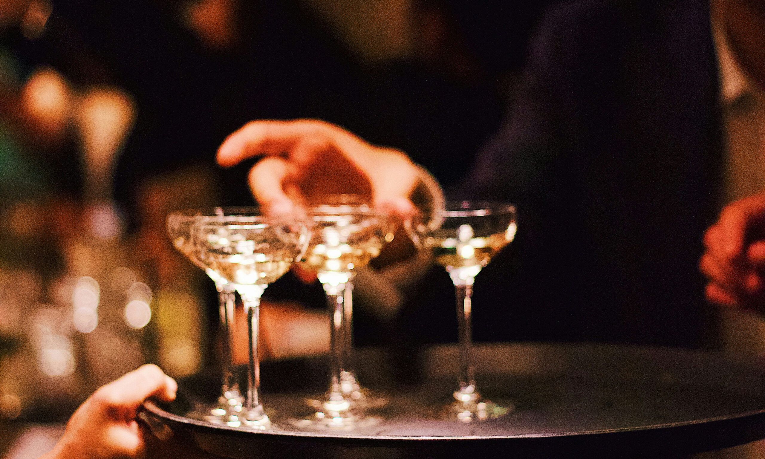 hand grabbing champagne glasses from a tray