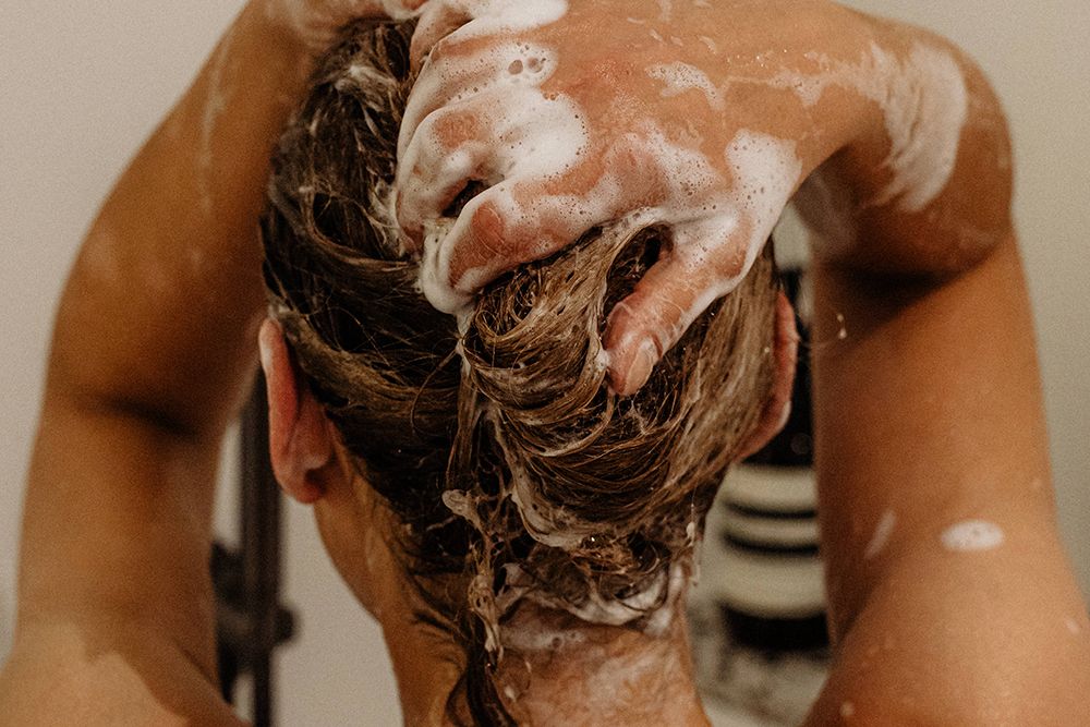 back view of woman washing hair with shampoo