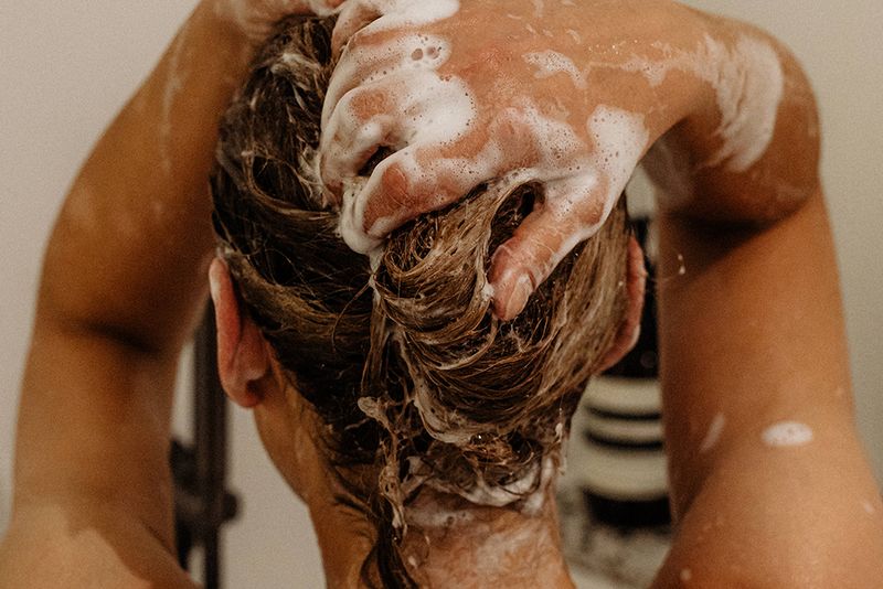 back view of woman washing hair with shampoo