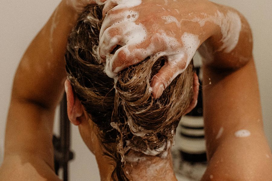 back view of woman washing hair with shampoo