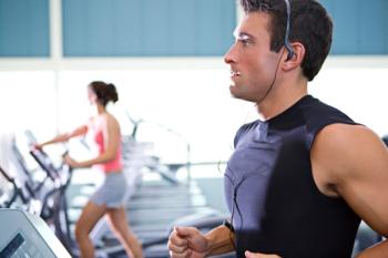 man with headphones on running on treadmill at the gym
