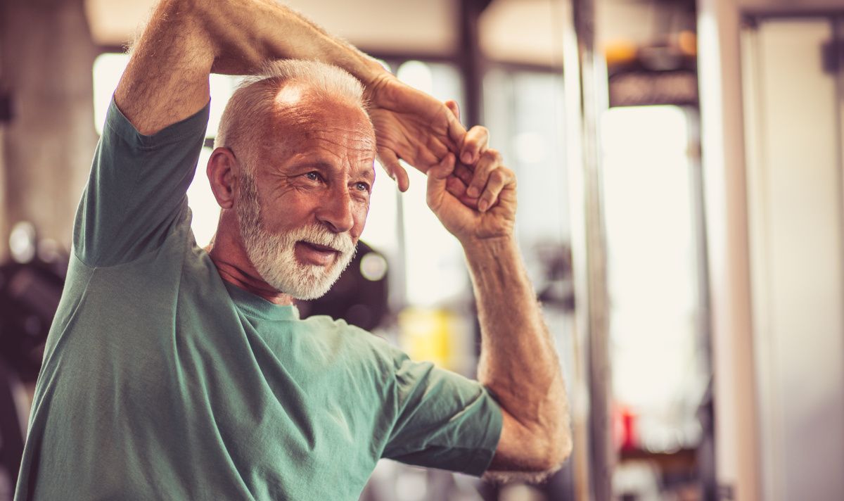 older man stretching in a gym