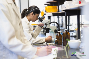 woman in lab looking through microscope