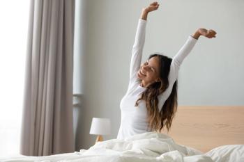 well rested woman stretching in bed
