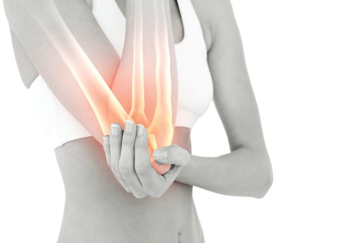 woman clutches elbow, with bone shining orange in arm