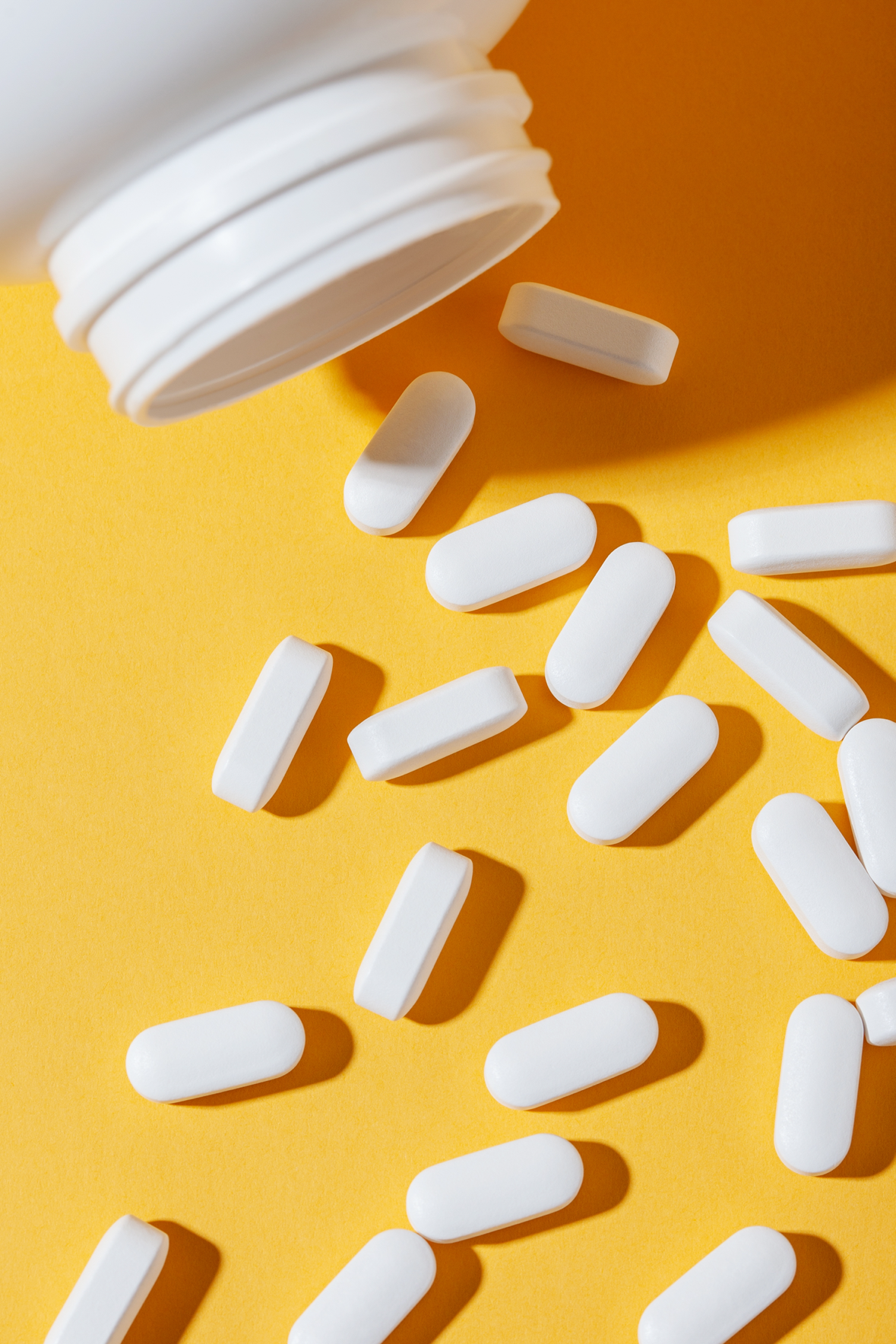bottle and white tablets on yellow background