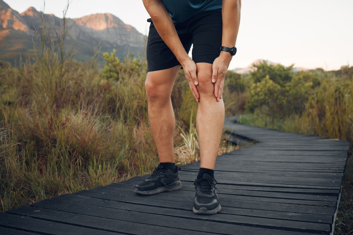 man holding knee on boardwalk