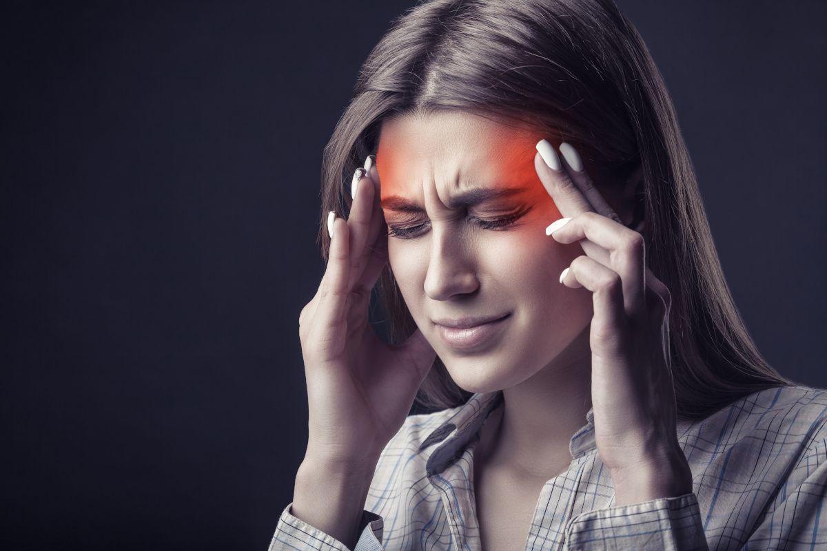 woman pressing fingers against temple in pain
