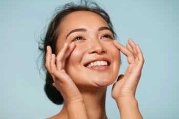 Skin care. Woman with beauty face touching healthy facial skin portrait. Beautiful smiling asian girl model with natural makeup touching glowing hydrated skin on blue background