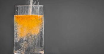 Orange colored sweetener being poured into a glass of water