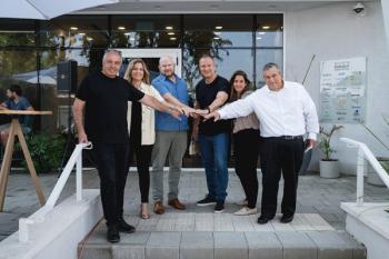 Six people huddled together with hands in touching in the middle in show of unity