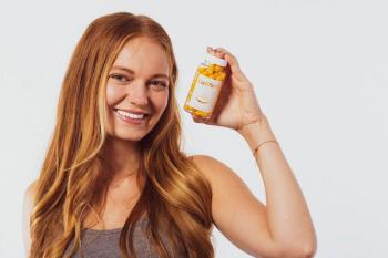young woman with red hair smiling and hold up Clear Within supplement