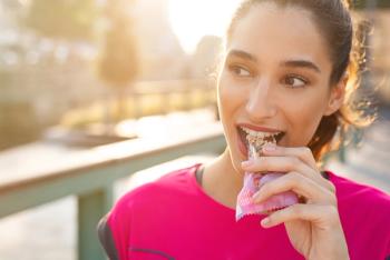 woman wearing pink shirt eating a bar at golden hour