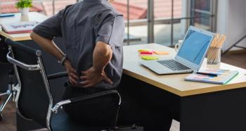 man at desk clutching lower back