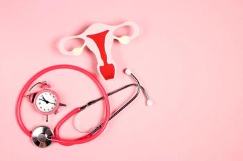 Women's health awareness concept. Uterus symbol with stethoscope and alarm clock on pink background.