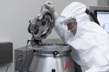 worker in ACG facility in protective equipment looking at machinery