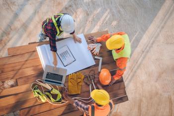 overhead view of three construction workers looking at blueprint