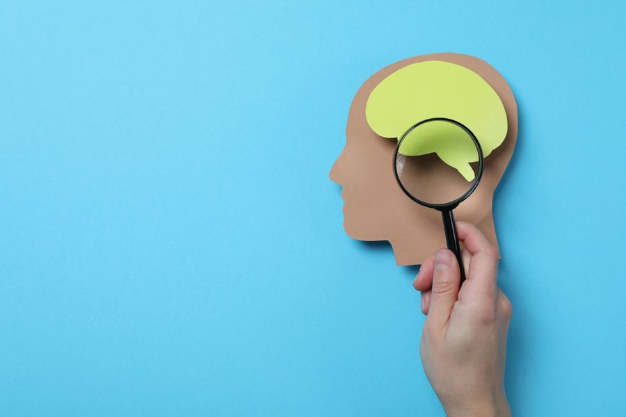 paper cutout of head and brain under magnifying glass