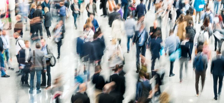 trade show floor. slow shutter speed with blurred human figures milling about.