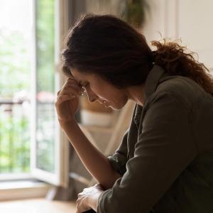 Photo of a woman with her hand on her forehead in stress