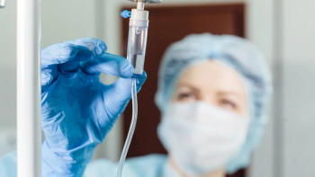 Image of an IV tube in focus, with a nurse in the background holding the tube