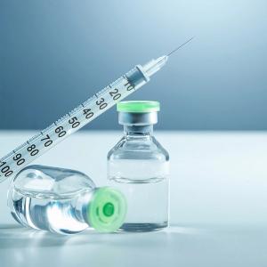 Photo of a syringe and a vaccine bottle