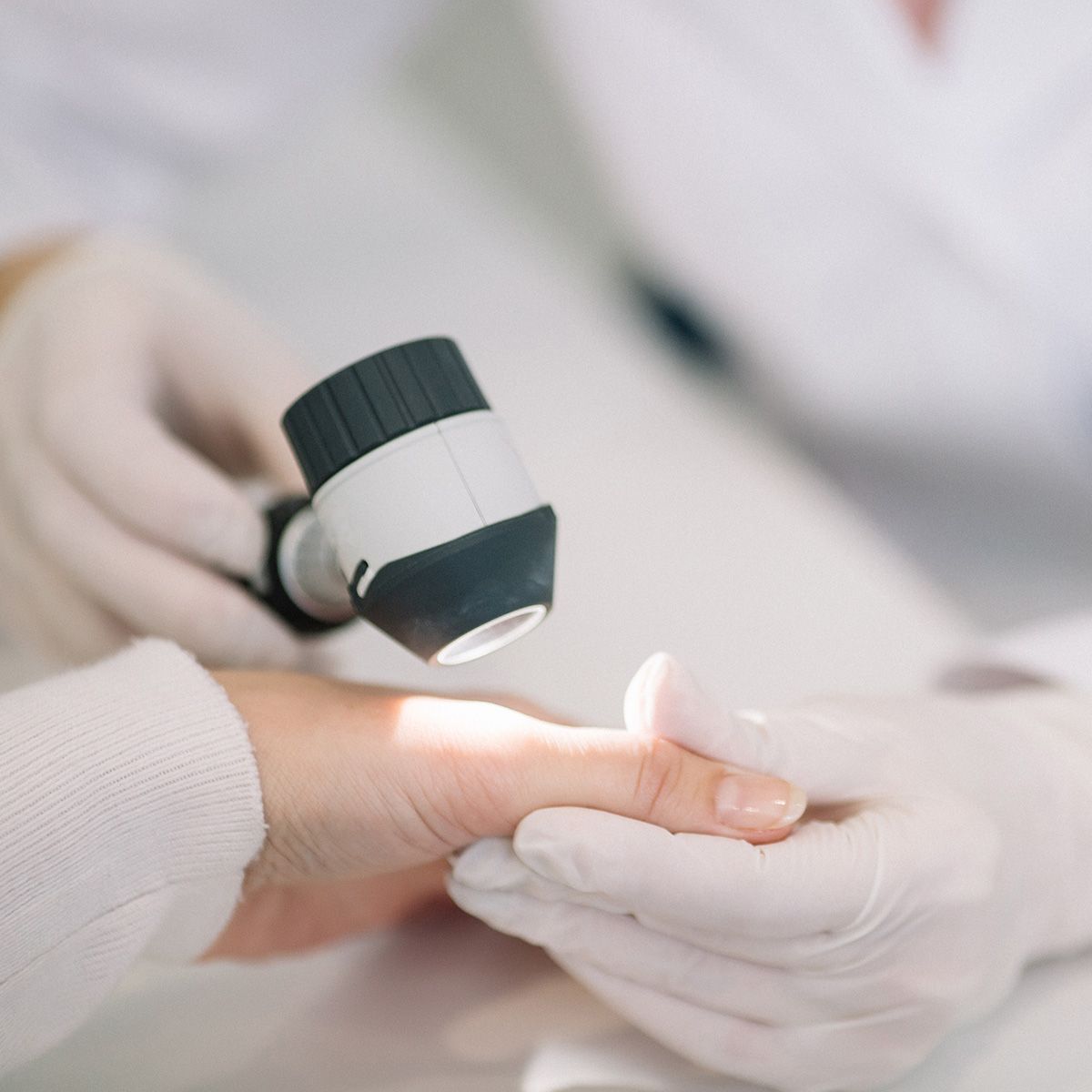 Photo of a person's hand being examined by a person in medical clothes