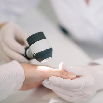 Photo of a person's hand being examined by a person in medical clothes