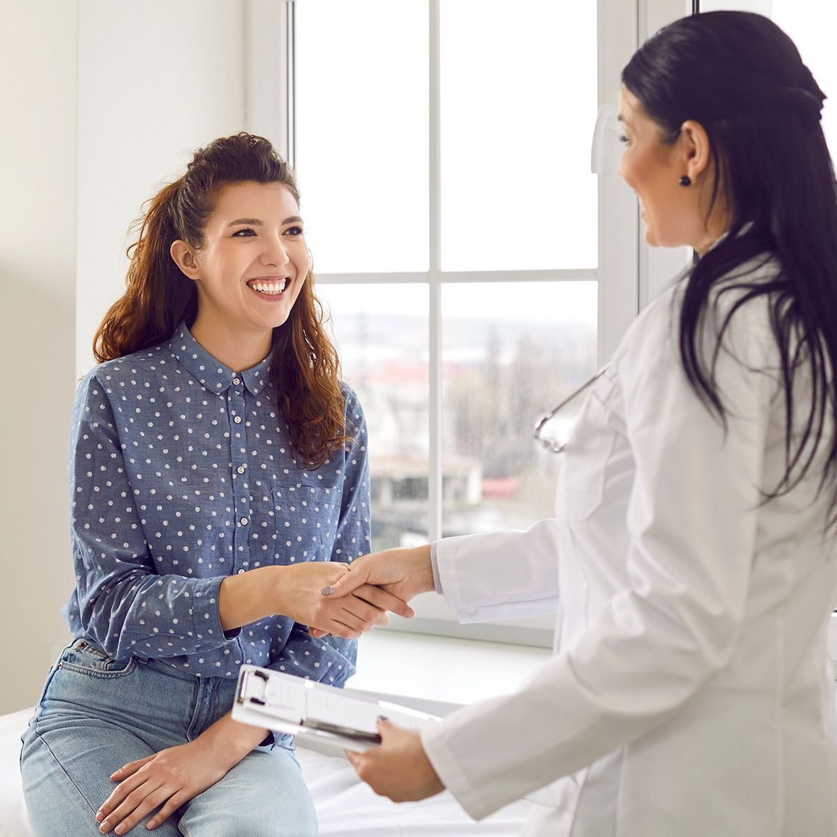 Photo of a young woman shaking hands with a healthcare provider in a doctor's office