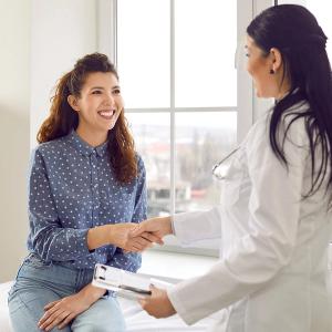 Photo of a young woman shaking hands with a healthcare provider in a doctor's office
