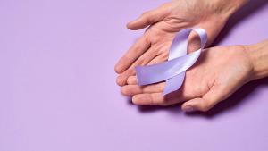 Image of two hands holding a purple ribbon in front of a purple background