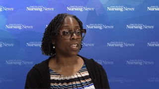 Image of a woman with glasses wearing a striped blouse and a black sweater in front of an Oncology Nursing News branded backdrop