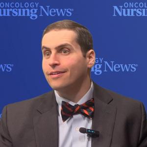 Photo of a man wearing a suit with a bowtie in front of an Oncology Nursing News backdrop