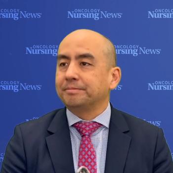 Image of a man in a suit standing in front of a blue Oncology Nursing News backdrop